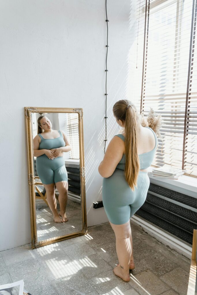 woman looking at body in mirror