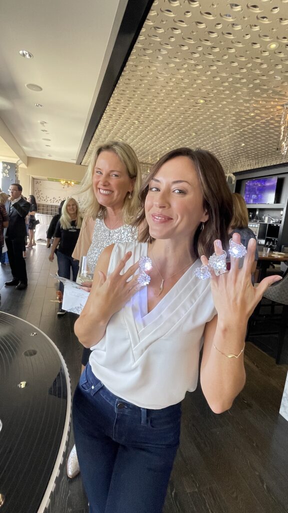 Woman smiling and showing off sparkling rings at Diamonds & Denim fundraiser in San Diego