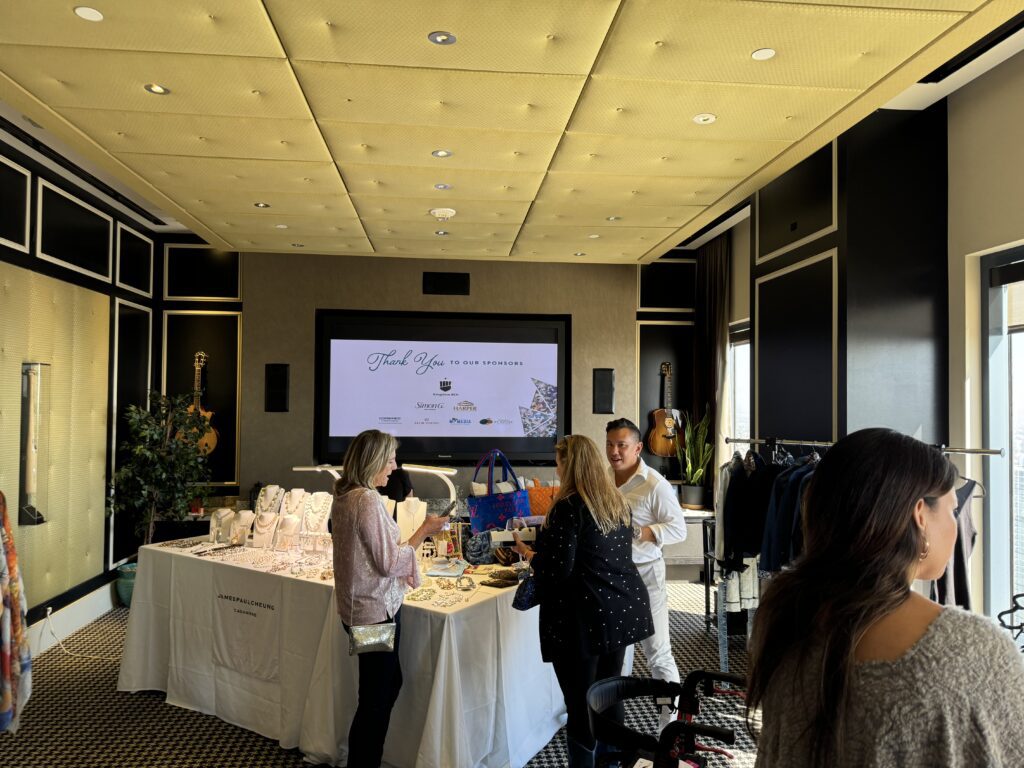 Guests browsing jewelry and fashion booths at Diamonds & Denim 2025 San Diego women’s fundraiser, with sponsor thank-you screen in background