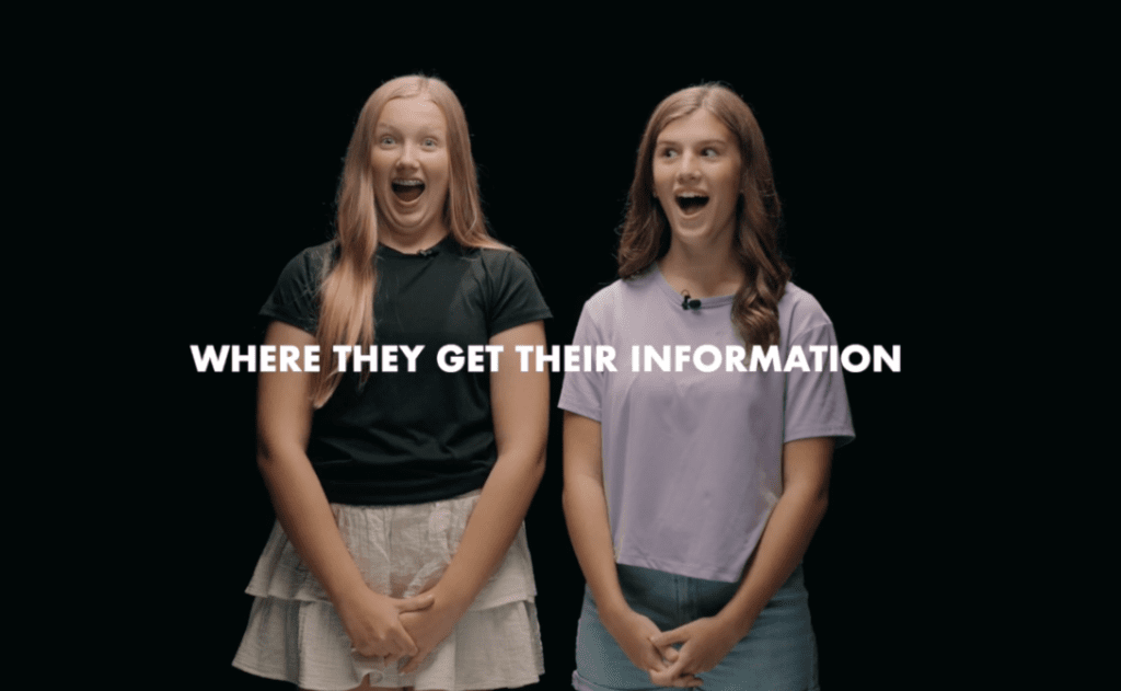 Two teenage girls react with surprise while discussing where they get their information, highlighting the importance of trusted health education and resources for young women.