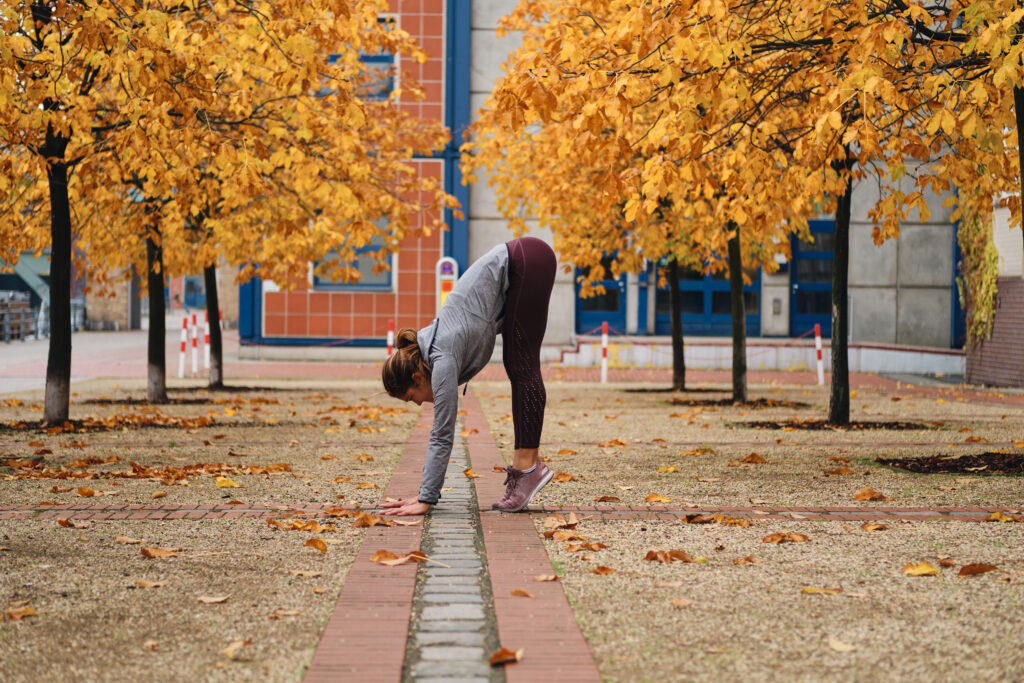 Woman stretching outdoors during an autumn workout.