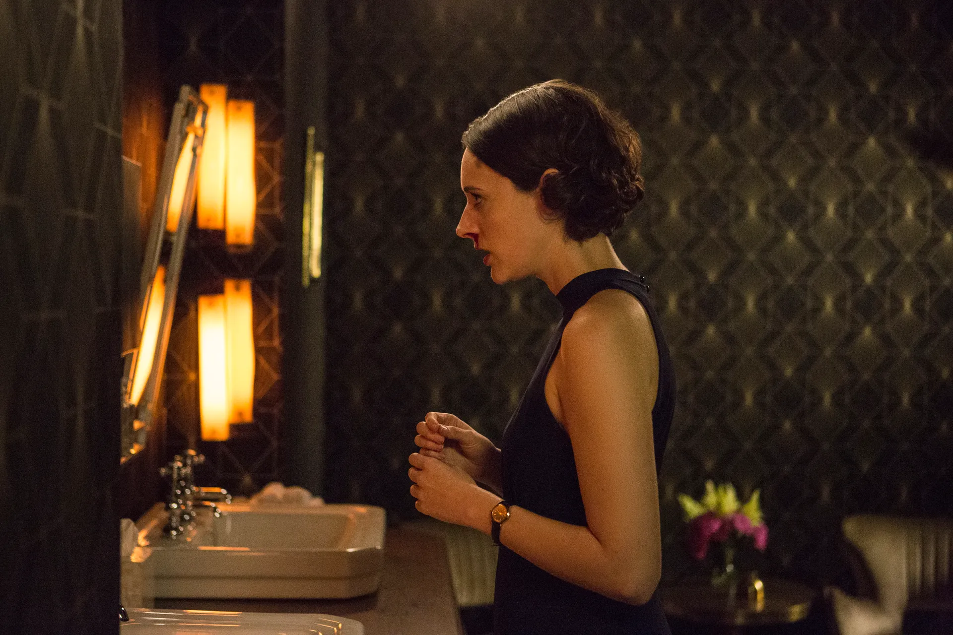 Woman standing alone in a restroom during an emotional scene from Fleabag.