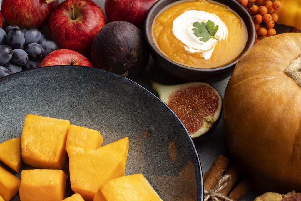 Autumn foods including pumpkin soup, squash, apples, grapes, figs, and pumpkin.
