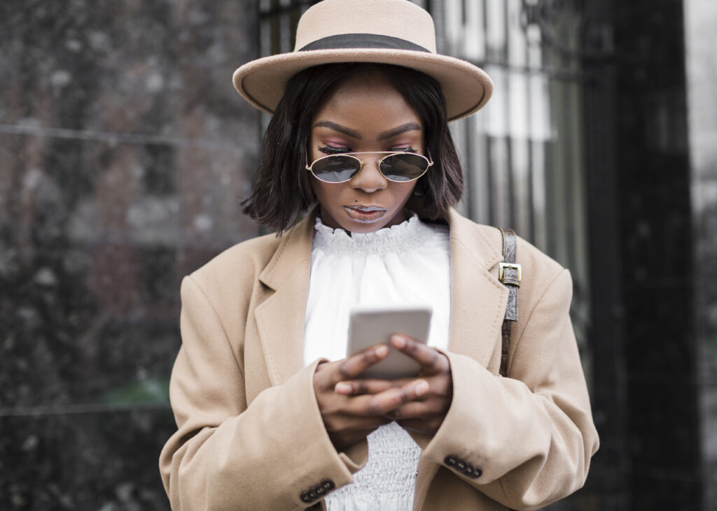Woman looking down at her smartphone while standing outdoors.